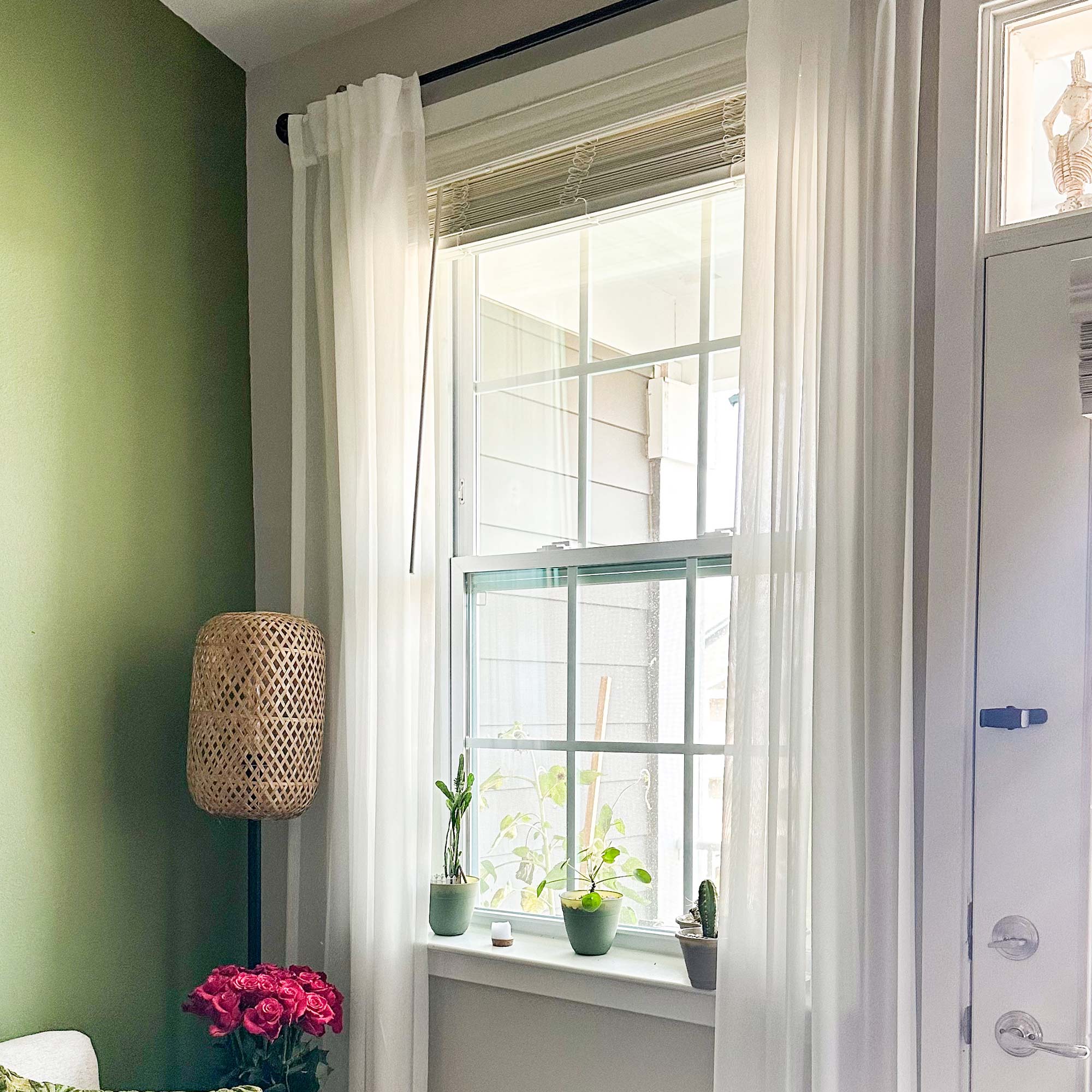 Weiß,Fenster mit weißen Vorhängen, Pflanzen und einem Korb an einer grünen Wand.