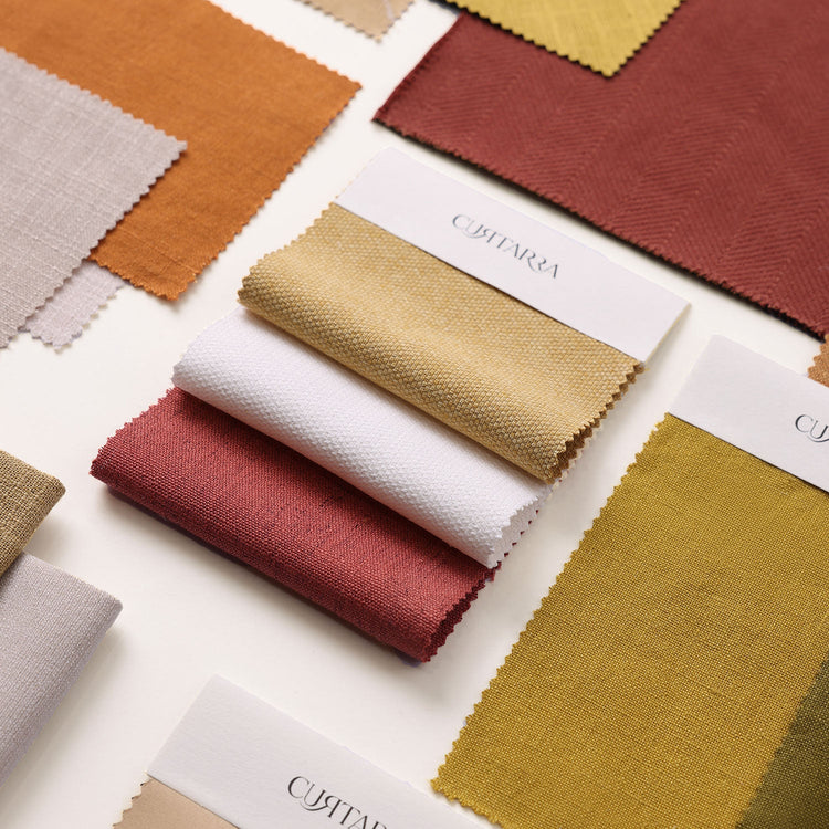 Flatlay vieler Curtarra Stoffmuster in verschiedenen Farben und Webarten mit Curtarra Musterkarten.